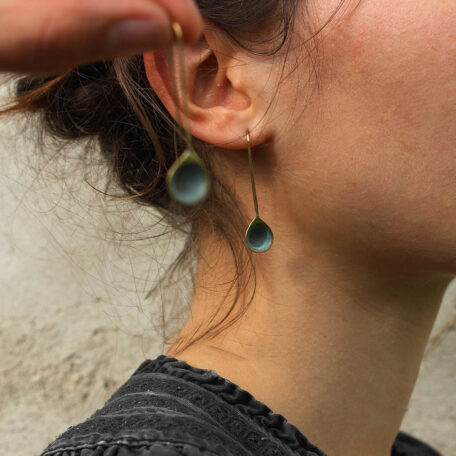 Boucles d’oreilles gouttelettes d'eau, en laiton fabriquées artisanalement par les Métalleuses en fusion. Vue sur l'oreille.