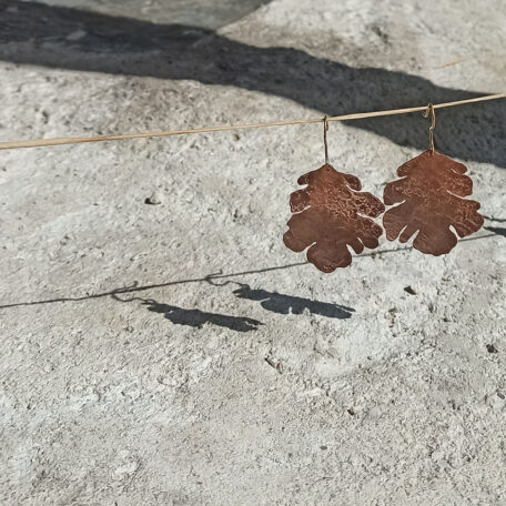 Boucles d'oreilles feuilles de chêne en cuivre, avec attaches en argent, fabriquées artisanalement par Les Métalleuses en fusion. Vue de face.