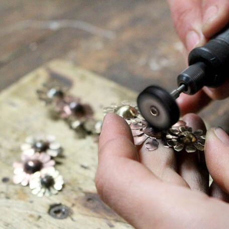 Boucle d'oreille Marguerites en cuivre laiton et argent, fabriquées artisanalement par les Métalleuses en fusion, photo en atelier.