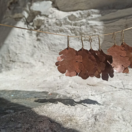 Boucles d'oreilles feuilles de chêne en cuivre, avec attaches en argent, fabriquées artisanalement par Les Métalleuses en fusion. Plusieurs paires, vue de coté.