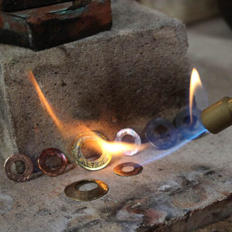 Recuit au chalumeau des boucles d'oreilles Tibet, en cuivre et laiton. Elles sont fabriquées artisanalement par les Métalleuses en fusion.